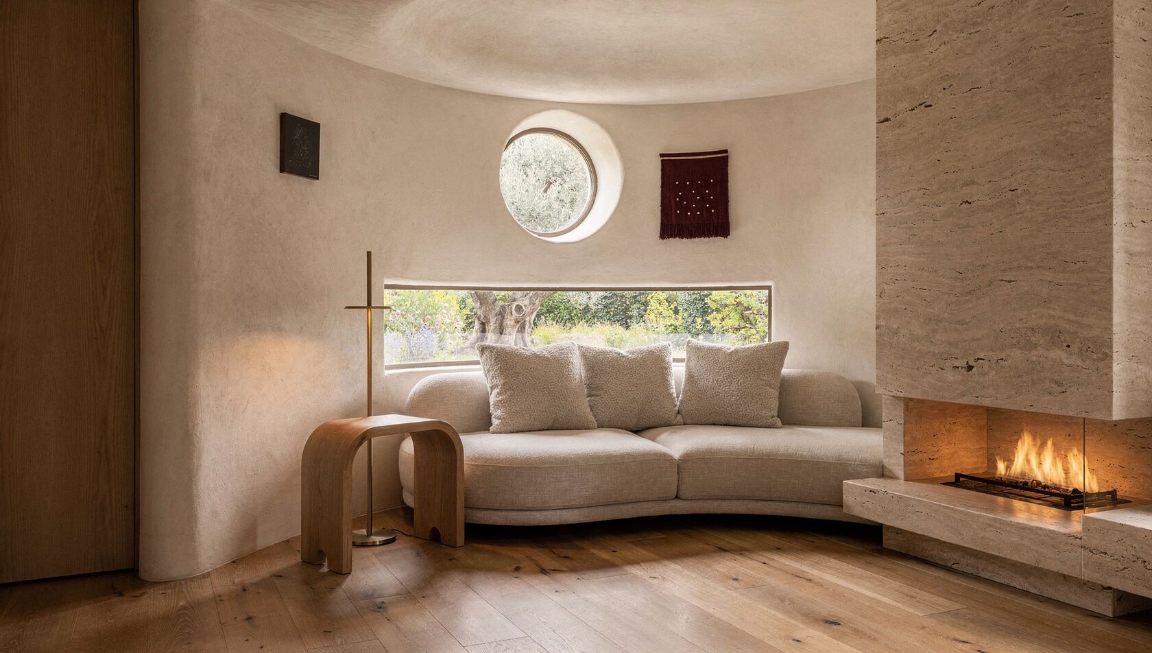 A Meshronix show-home reading snug, a curved plaster wall and quiet fire, calm and lived-in